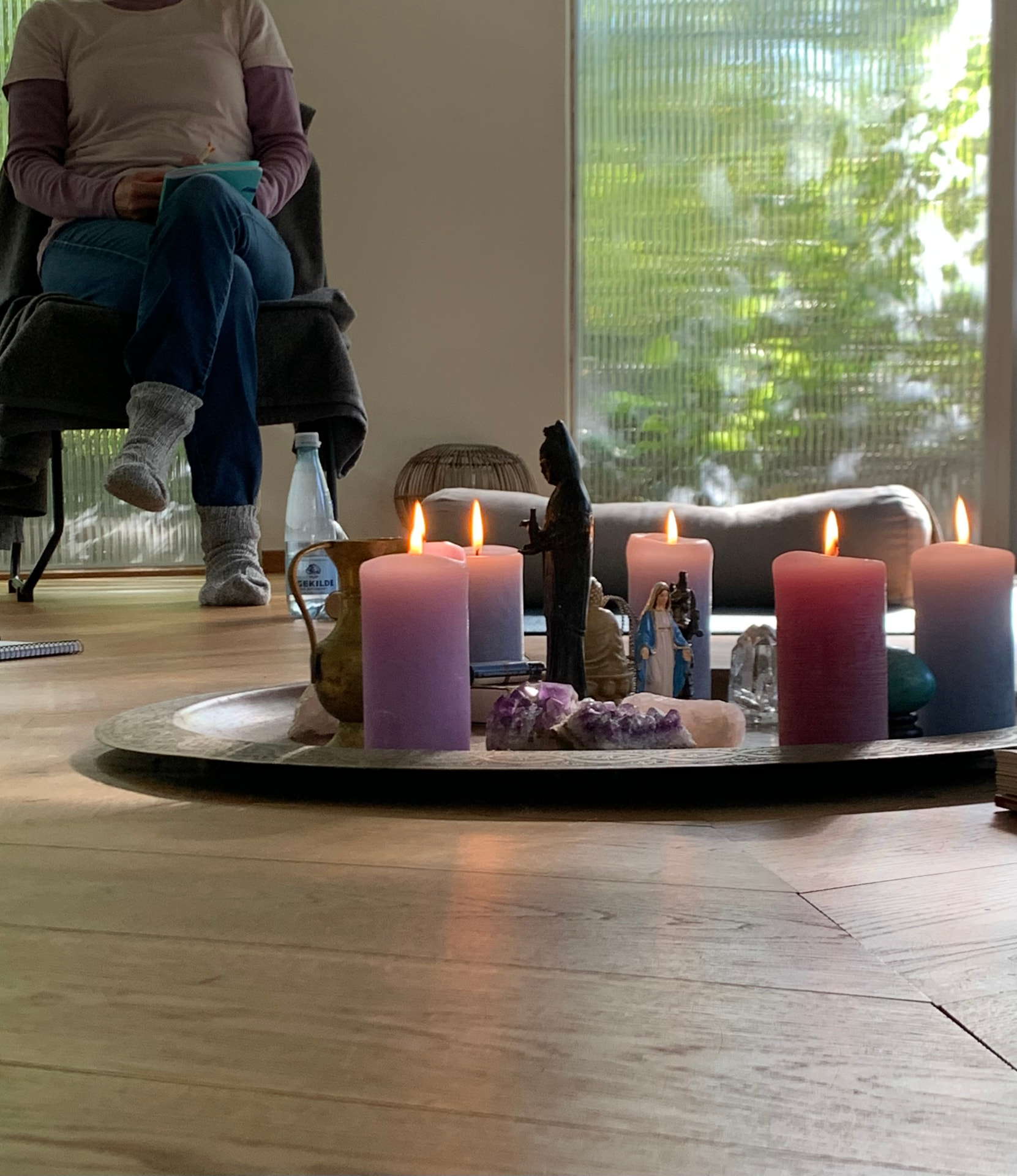 Meditation med levende lys, krystaller og figurer på et bord